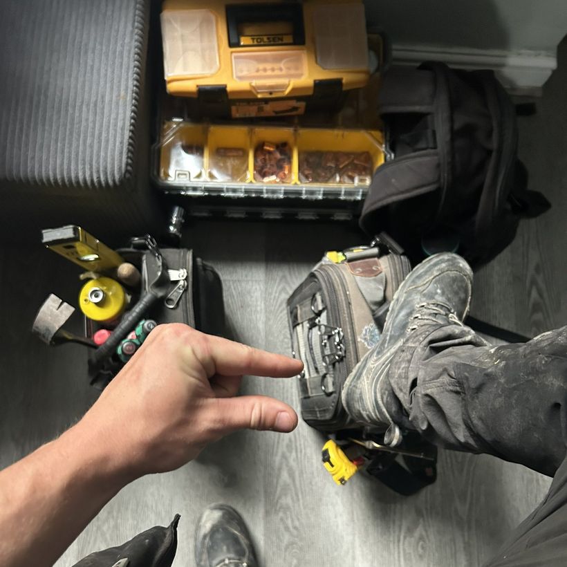 His tool bag, toolbox and dusty work boot on the floor